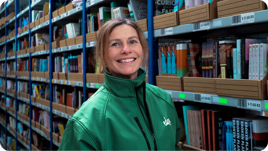 An Eden team member standing among warehouse book shelves